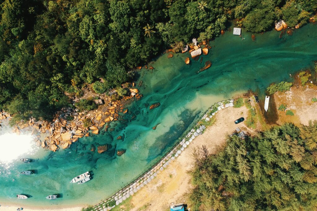 Stunning aerial view of a turquoise river lined with lush forest and boats, perfect for travel inspiration.