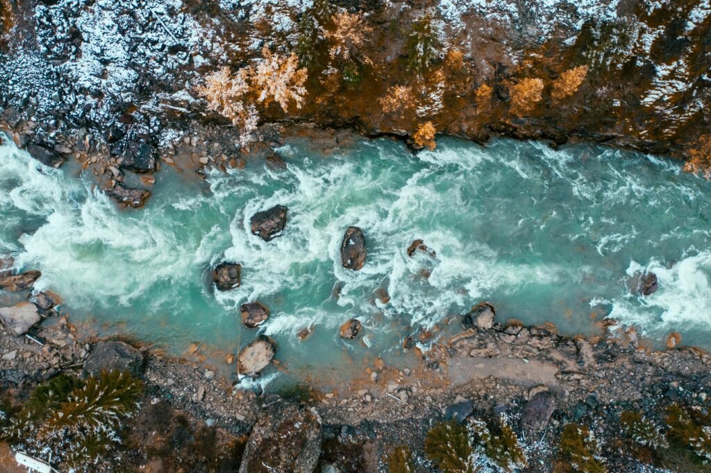 Stunning aerial shot of a turquoise river flowing through snowy terrain in Altai, Russia.